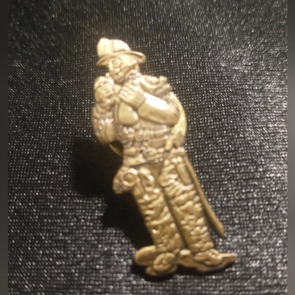 Firefighter holding a child lapel pin. Rare find in gold tone unique as them.